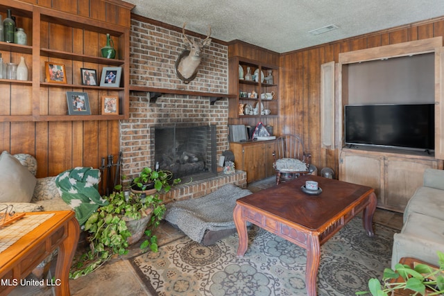 living room with built in features, a brick fireplace, a textured ceiling, and wood walls