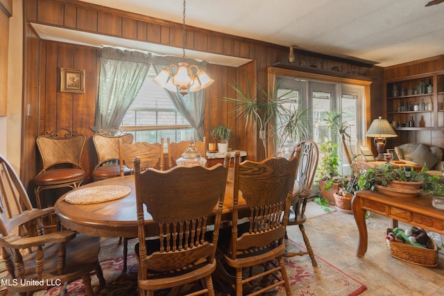 dining area with a notable chandelier and wood walls