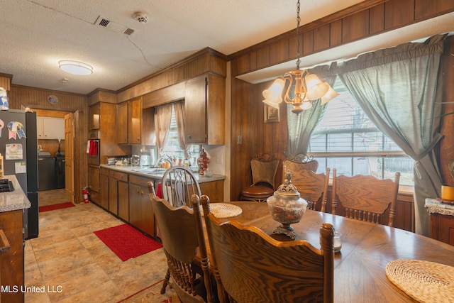 dining area featuring a notable chandelier, sink, a textured ceiling, and wood walls