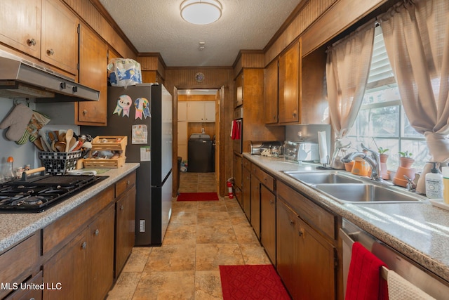 kitchen featuring appliances with stainless steel finishes, washer / dryer, sink, crown molding, and a textured ceiling