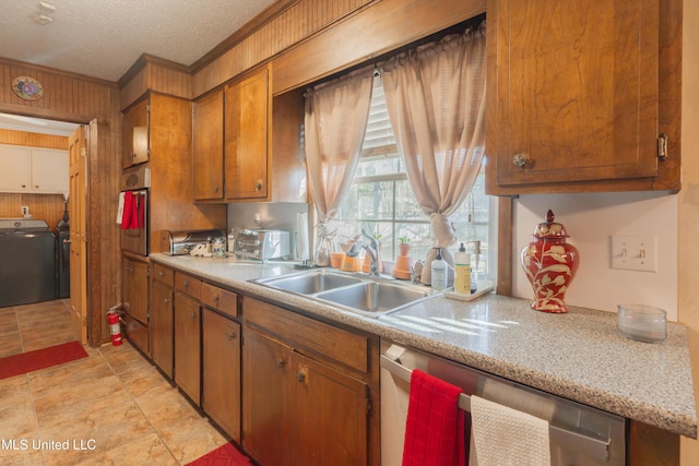 kitchen featuring sink, crown molding, stainless steel appliances, a textured ceiling, and washing machine and clothes dryer