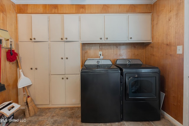 laundry area featuring cabinets, wooden walls, and washer and dryer