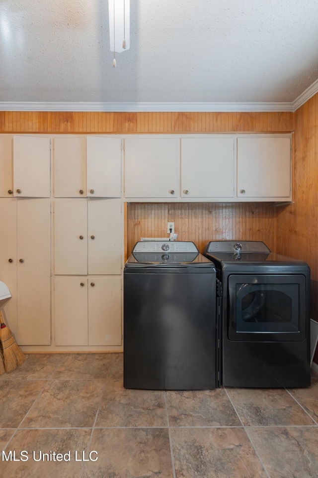 washroom with independent washer and dryer, cabinets, ornamental molding, a textured ceiling, and wood walls