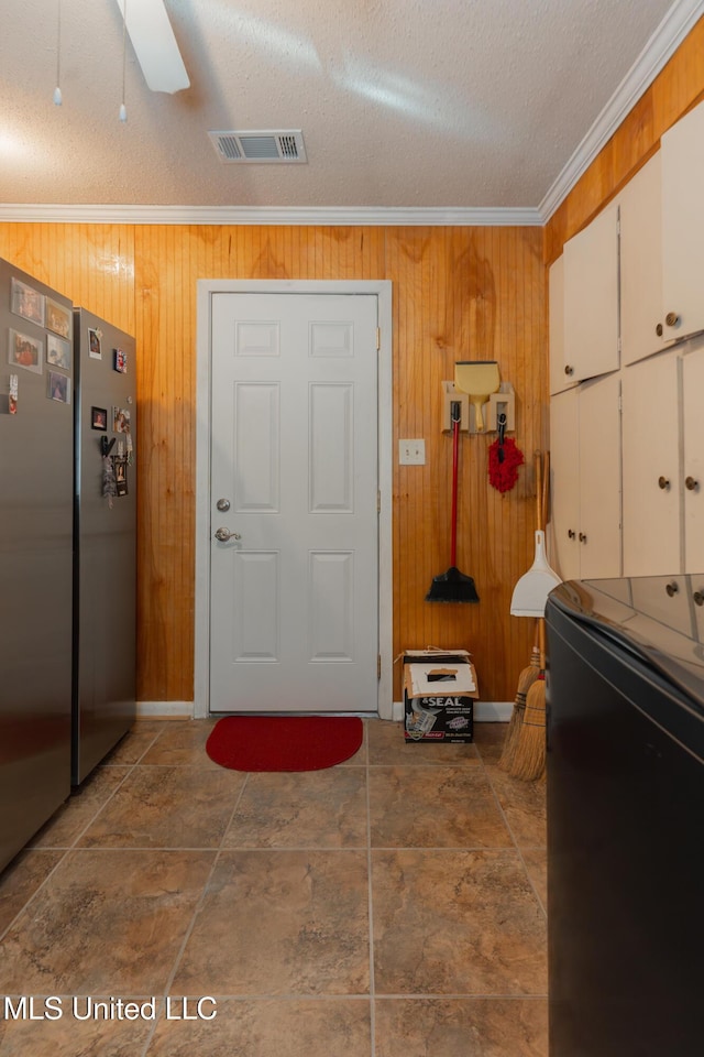 entryway with ornamental molding, washer / dryer, wooden walls, and a textured ceiling