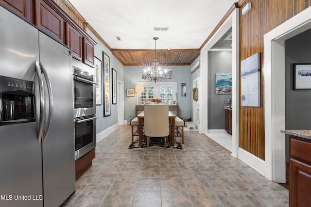 dining room featuring a notable chandelier, wood walls, and crown molding