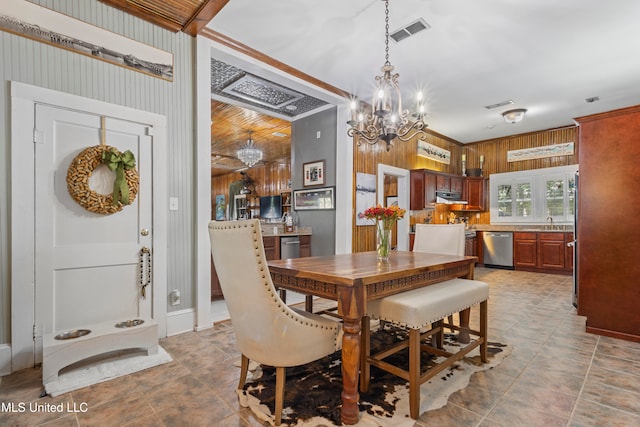 dining space with ornamental molding, sink, a chandelier, and wood walls