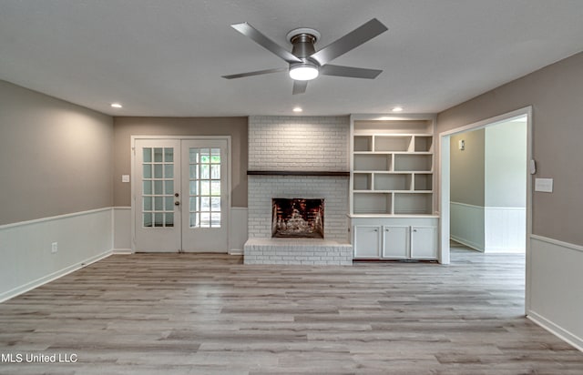 unfurnished living room featuring french doors, a fireplace, light hardwood / wood-style floors, and ceiling fan