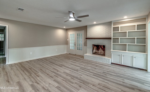 unfurnished living room with light hardwood / wood-style floors, french doors, a fireplace, and ceiling fan