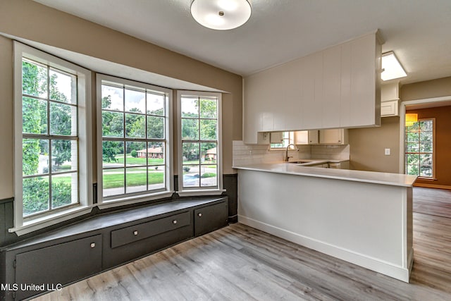 kitchen featuring light hardwood / wood-style flooring, white cabinets, tasteful backsplash, and a wealth of natural light