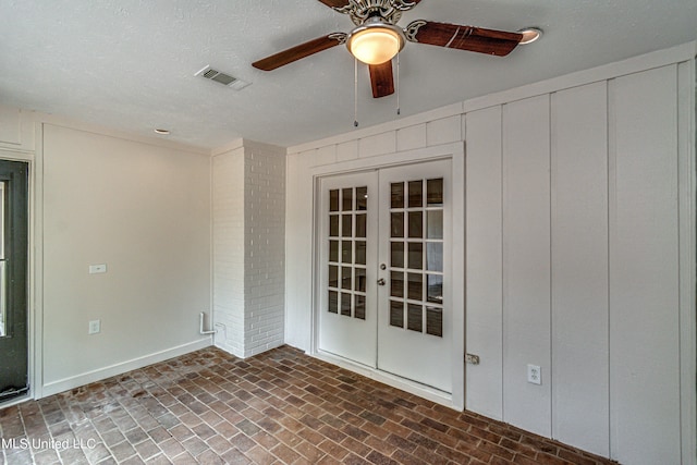 empty room featuring french doors, a textured ceiling, and ceiling fan