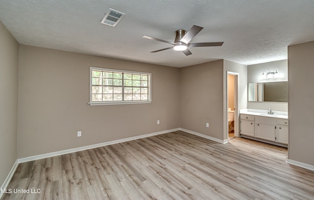 unfurnished bedroom featuring light hardwood / wood-style flooring, sink, connected bathroom, and ceiling fan