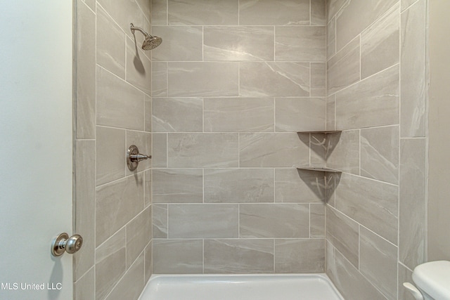 bathroom featuring a tile shower and toilet