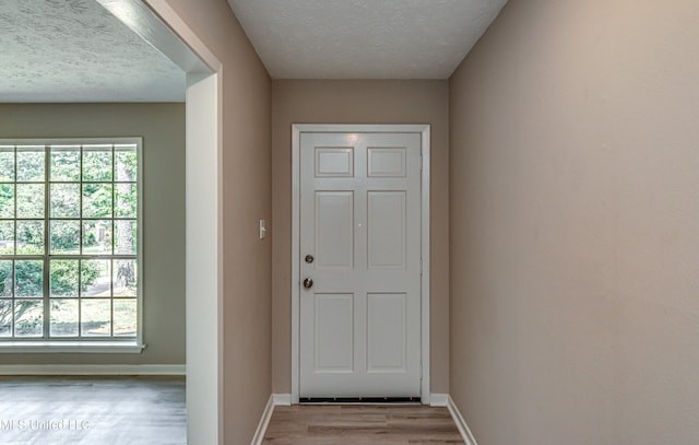 doorway with light hardwood / wood-style floors and a textured ceiling