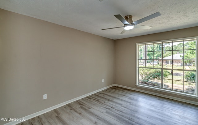 spare room with a textured ceiling, light wood-type flooring, and ceiling fan