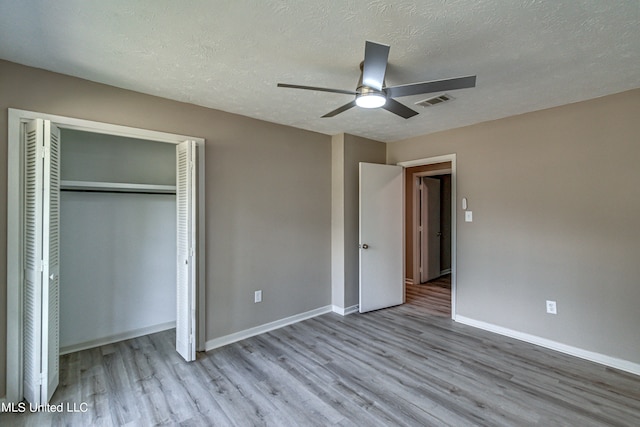 unfurnished bedroom featuring a closet, ceiling fan, a textured ceiling, and light wood-type flooring