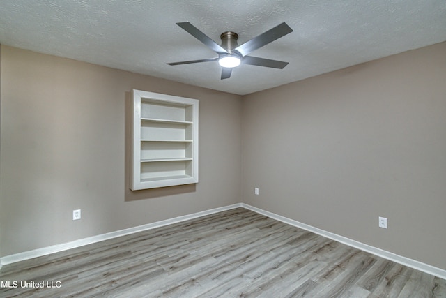 unfurnished room with light hardwood / wood-style floors, a textured ceiling, built in features, and ceiling fan