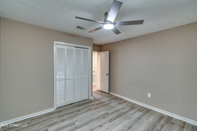 unfurnished bedroom with a closet, a textured ceiling, light wood-type flooring, and ceiling fan