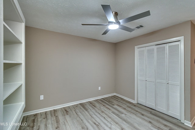 unfurnished bedroom with a closet, a textured ceiling, light wood-type flooring, and ceiling fan