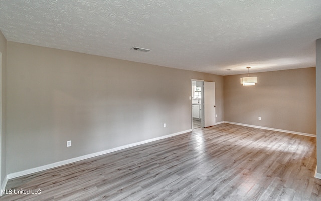 unfurnished room with a textured ceiling and light hardwood / wood-style flooring