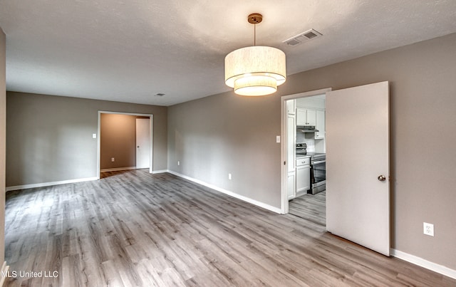 unfurnished room with light hardwood / wood-style floors and a textured ceiling