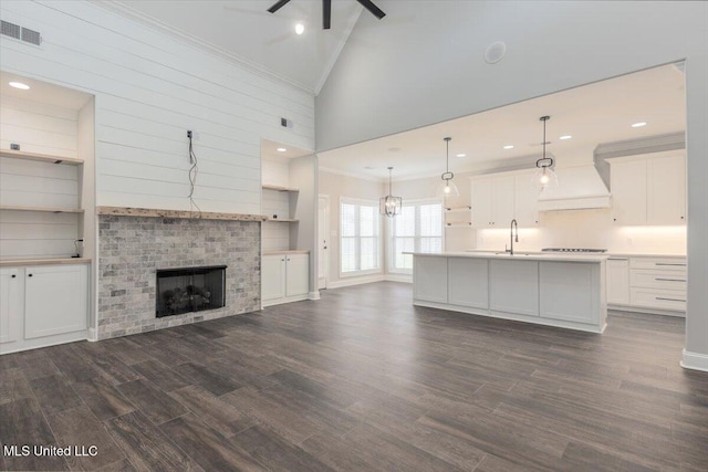unfurnished living room featuring visible vents, crown molding, ceiling fan, dark wood-style floors, and a sink