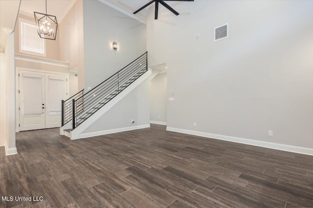 unfurnished living room featuring visible vents, stairs, a high ceiling, and an inviting chandelier