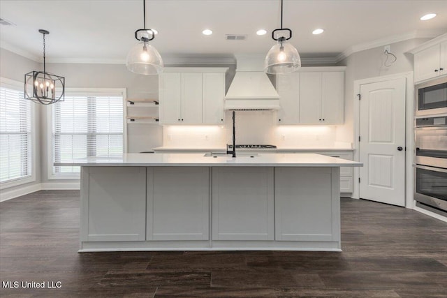 kitchen with light countertops, white cabinets, an island with sink, and premium range hood