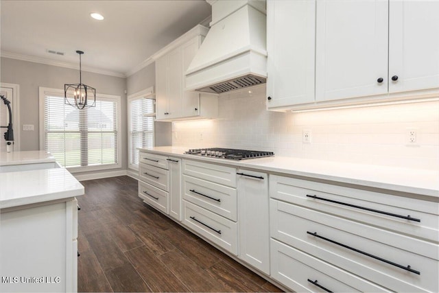 kitchen with a notable chandelier, premium range hood, white cabinetry, backsplash, and visible vents