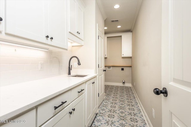 washroom featuring visible vents, baseboards, recessed lighting, a sink, and cabinet space