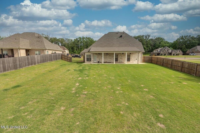 back of house featuring a lawn, brick siding, a fenced backyard, and a patio area