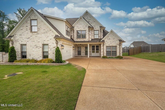 view of front facade with a front lawn, fence, brick siding, an attached garage, and driveway