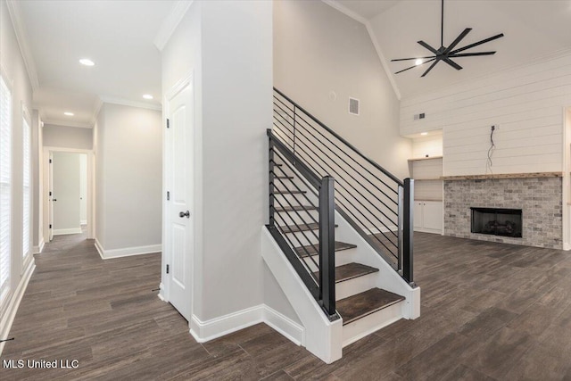 staircase with visible vents, ornamental molding, a brick fireplace, and wood finished floors