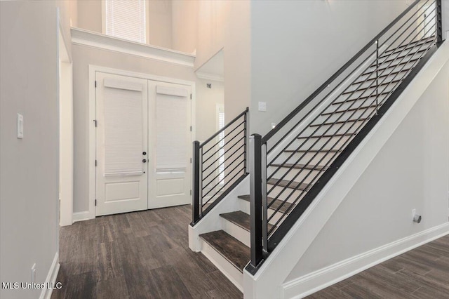 foyer featuring baseboards, wood finished floors, and stairway
