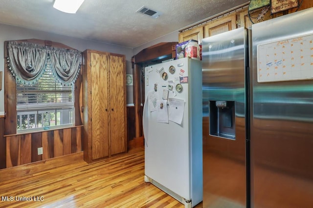 kitchen featuring stainless steel fridge with ice dispenser, a textured ceiling, light wood-style flooring, freestanding refrigerator, and visible vents