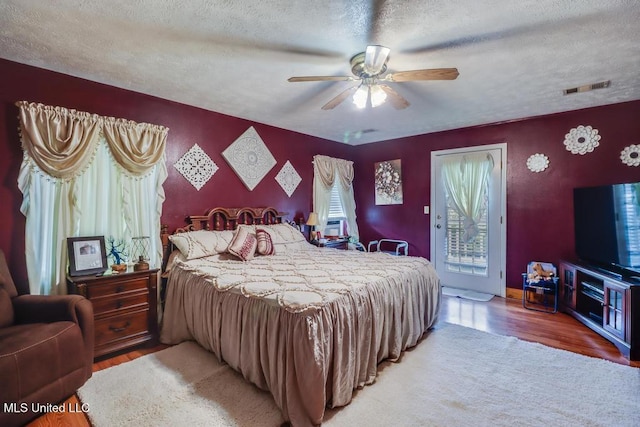 bedroom with access to outside, light wood-style flooring, a textured ceiling, and visible vents