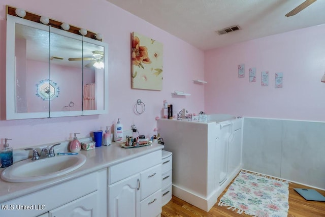 bathroom with vanity, ceiling fan, wood finished floors, and visible vents
