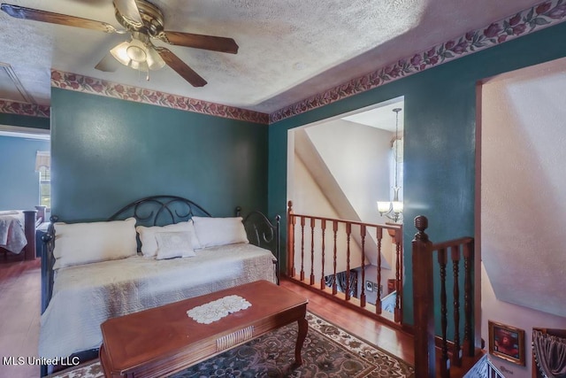 bedroom with a ceiling fan, a textured ceiling, and wood finished floors