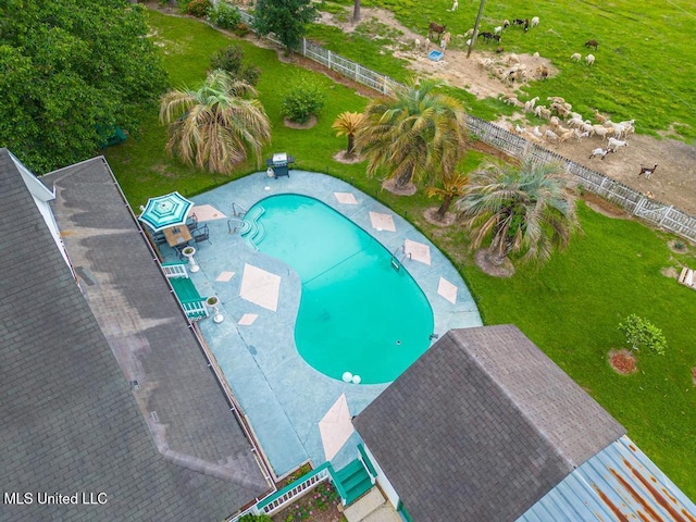 community pool with a patio, fence, and a yard