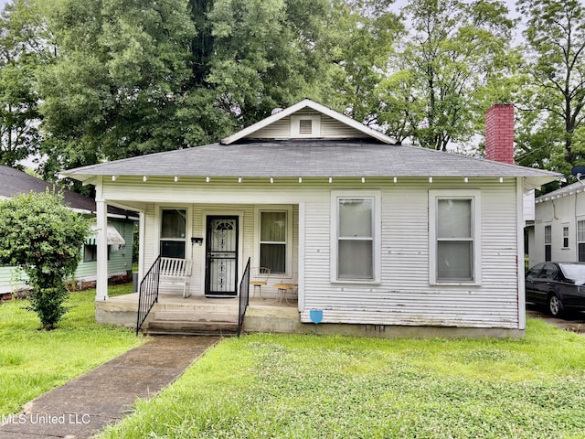 1205 Leflore Ave, Greenwood, MS 38930 - view of front of home with a porch, a front yard, a chimney, and a shingled roof