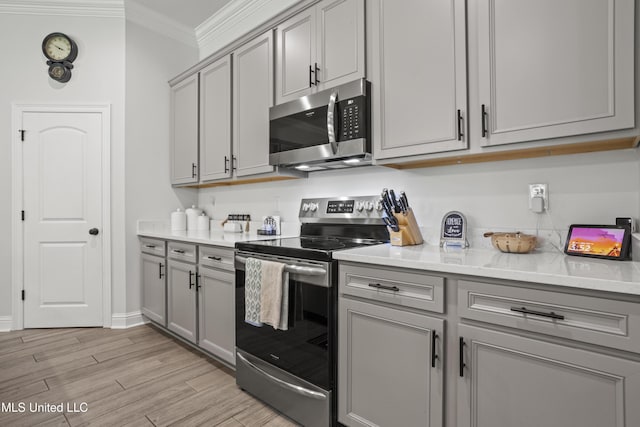 9363 Taylor Pl, Ocean Springs, MS 39564 - kitchen with stainless steel appliances, gray cabinetry, ornamental molding, light wood-style floors, and baseboards
