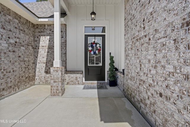 9363 Taylor Pl, Ocean Springs, MS 39564 - doorway to property featuring board and batten siding, brick siding, and roof with shingles