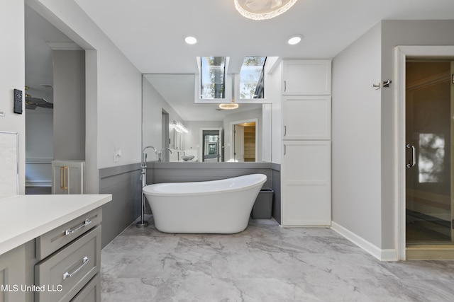 bathroom featuring vanity, a tub to relax in, and a skylight