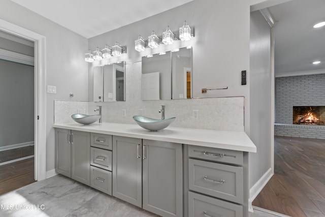 bathroom featuring vanity, hardwood / wood-style flooring, tasteful backsplash, and a fireplace