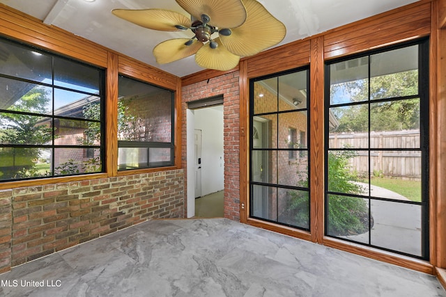 unfurnished sunroom with ceiling fan