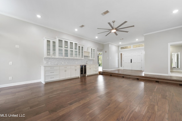 unfurnished living room with beverage cooler, ceiling fan, dark hardwood / wood-style floors, crown molding, and sink