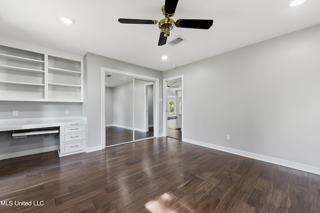 interior space with built in desk, dark hardwood / wood-style floors, a closet, and ceiling fan