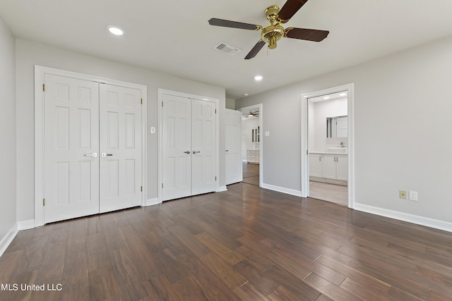 unfurnished bedroom with sink, ceiling fan, two closets, ensuite bathroom, and dark hardwood / wood-style flooring