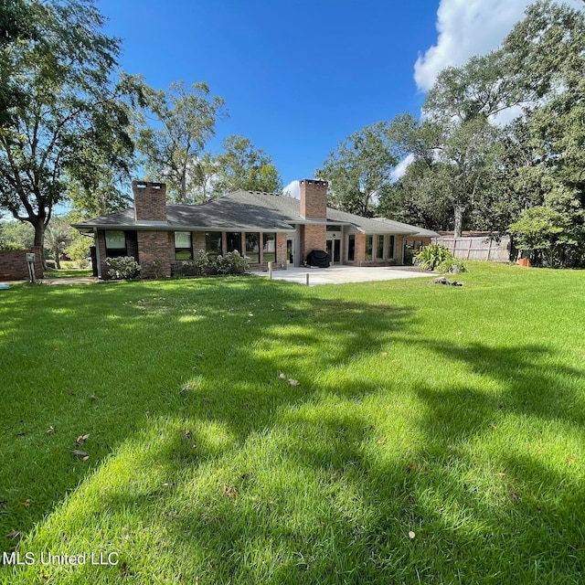 rear view of house featuring a patio and a lawn