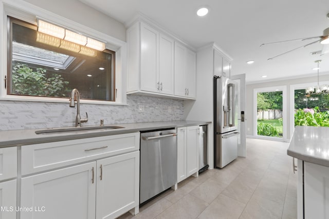 kitchen with white cabinets, backsplash, appliances with stainless steel finishes, a skylight, and sink