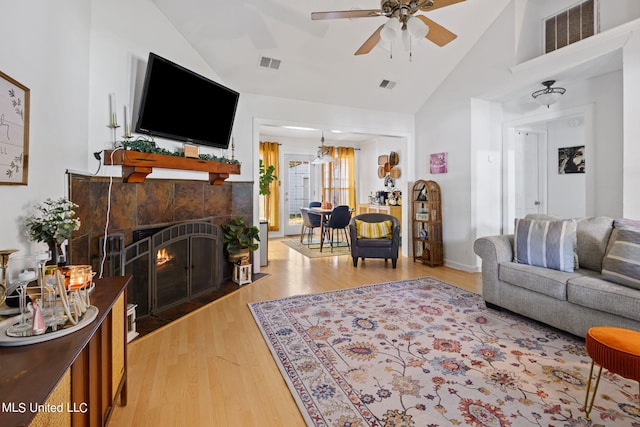 living room featuring a tiled fireplace, ceiling fan, high vaulted ceiling, and hardwood / wood-style floors